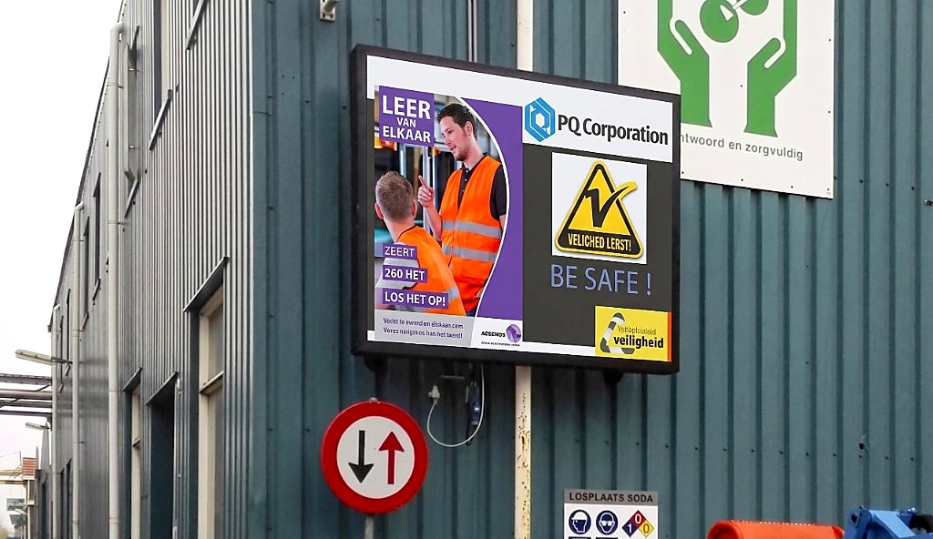 Outdoor veiligheidsscherm op fabriekssite met veiligheidsboodschap